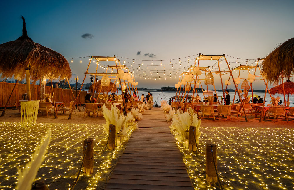 Cozy beachfront restaurant at sunset with string lights, bamboo decor, and ocean view. Perfect for a romantic evening.