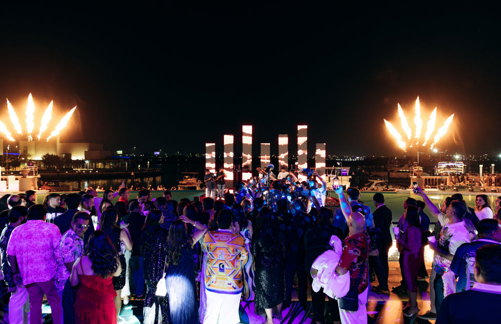 Crowd enjoying a vibrant outdoor party with fireworks lighting up the night sky.