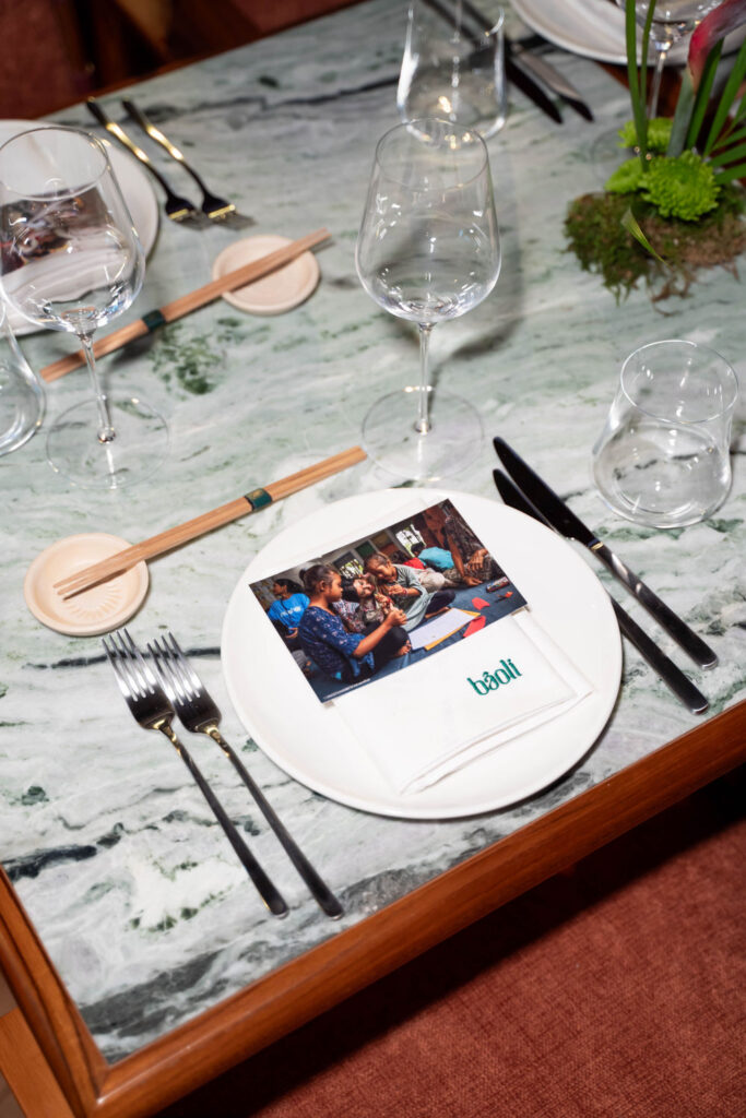 Elegant table setting with glassware, cutlery, and a Baali-branded napkin on a marble surface.