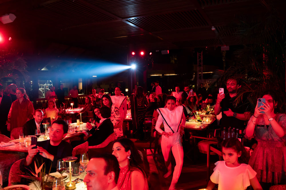 Attendees enjoying a vibrant party with red lighting and live entertainment in a lively, upscale venue setting.