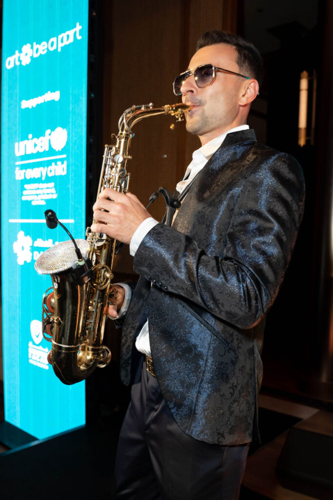 Musician playing saxophone at charity event supporting UNICEF.