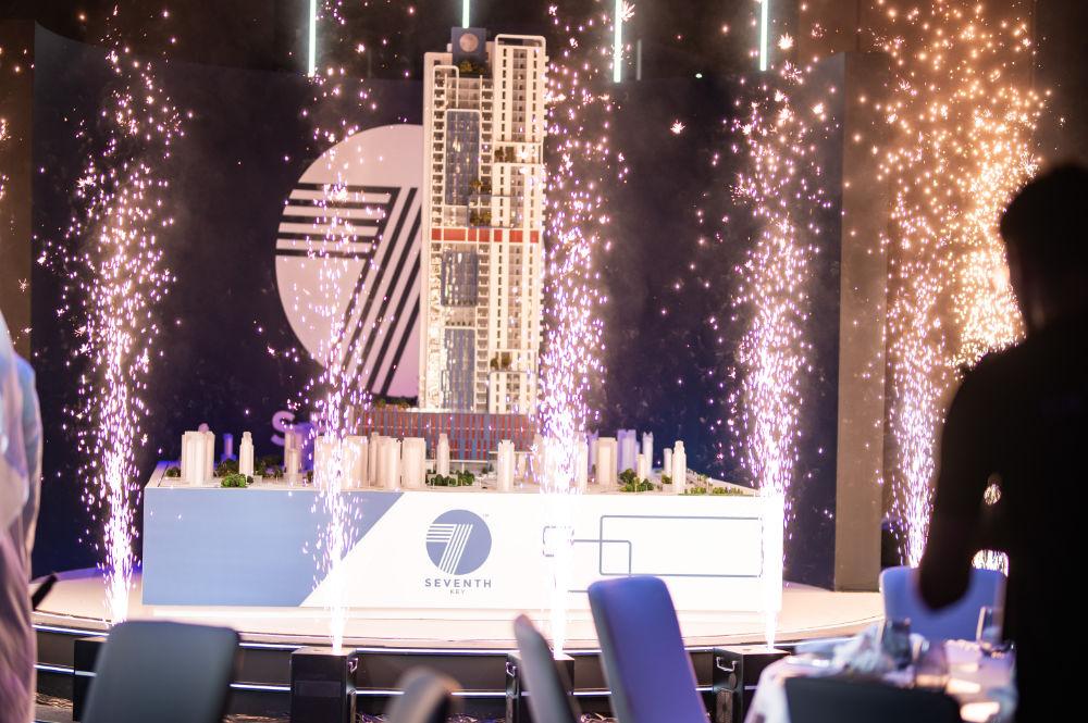 Skyscraper model displayed on stage with fireworks at a building unveiling event.
