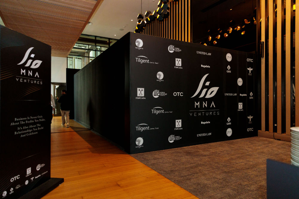 MNA Ventures event backdrop with logos and wooden flooring, emphasizing business partnerships and collaboration.