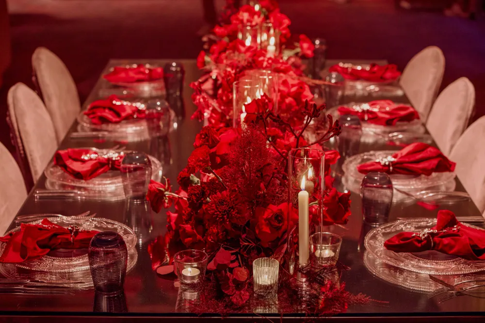 Elegant table setting with red flowers and candles, perfect for a romantic dinner or special occasion ambiance.