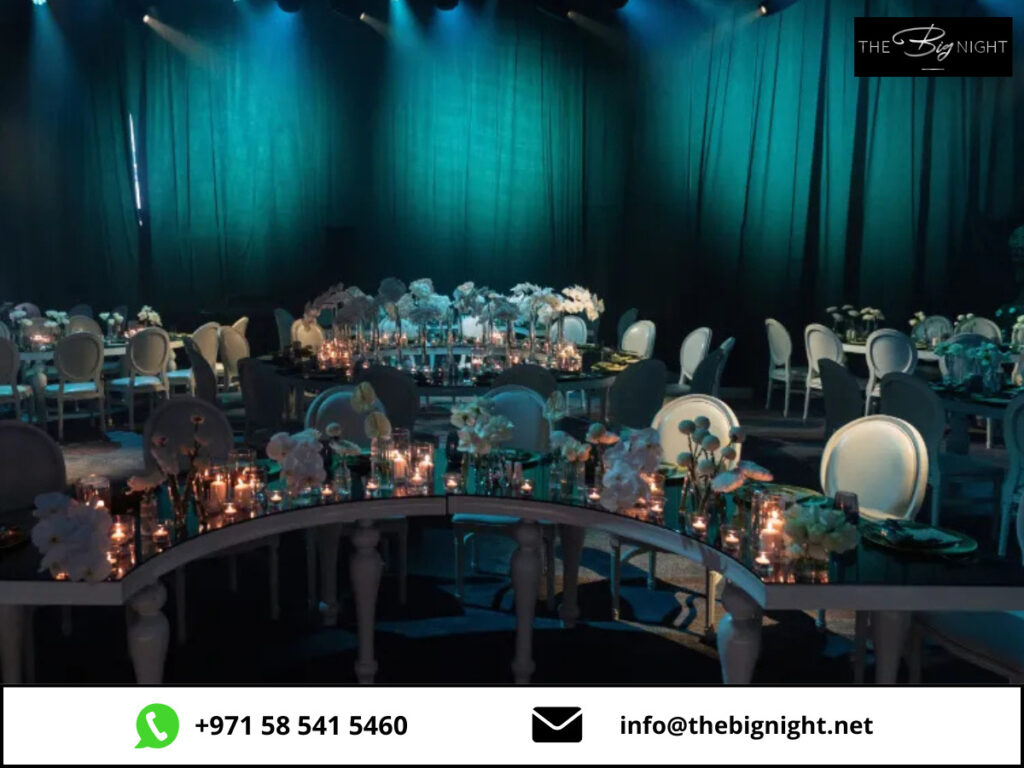 Elegant event setup with candlelit tables, floral arrangements, and ambient teal lighting at The Big Night venue.