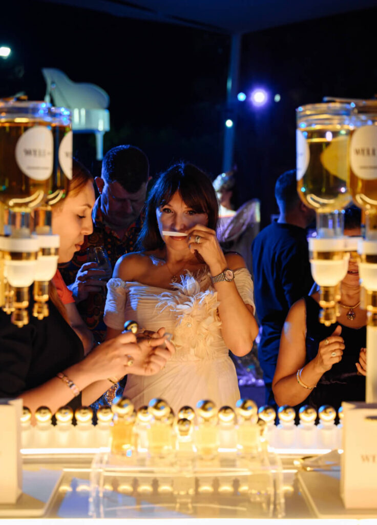 Designer perfume tasting event with guests sampling fragrances under elegant evening lighting.