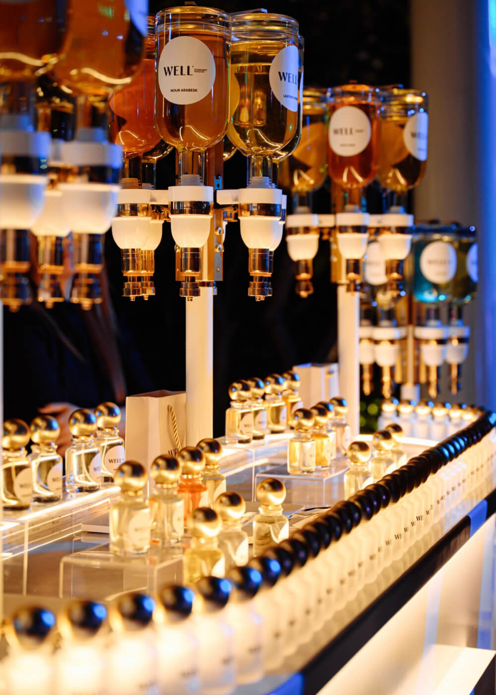 A stylish display of luxury perfume bottles with golden caps at an elegant, well-lit counter.