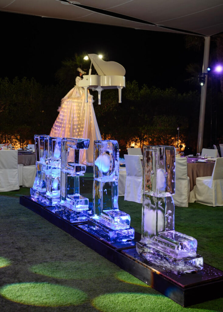Spectacular event with ice sculptures and a woman in a glowing dress playing a suspended grand piano.