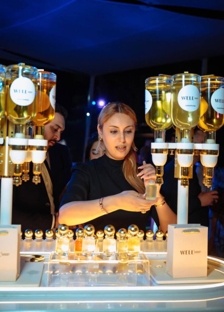Person sampling perfumes at a luxurious perfume bar with elegant glass bottles and gold accents.
