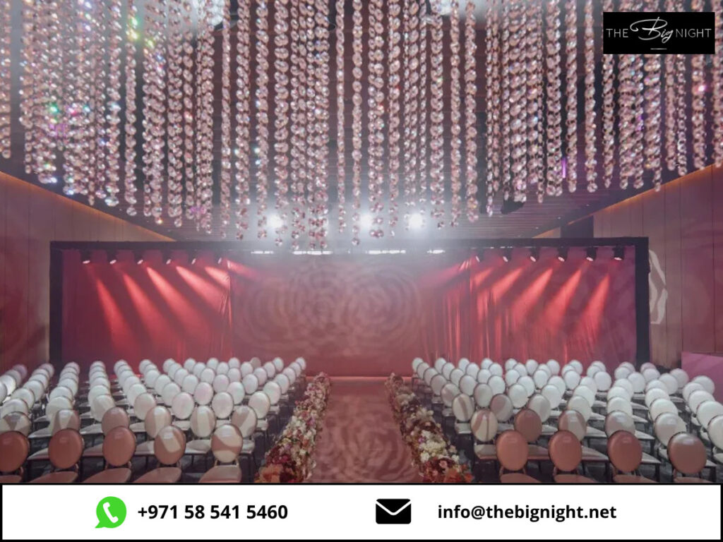 Elegant event setup with red drapes and floral aisle under sparkling ceiling lights. Contact via +971 58 541 5460.