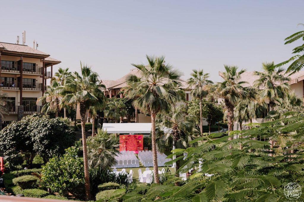 Garden wedding venue with palm trees, elegant seating, and vibrant decor set for a beautiful outdoor ceremony.