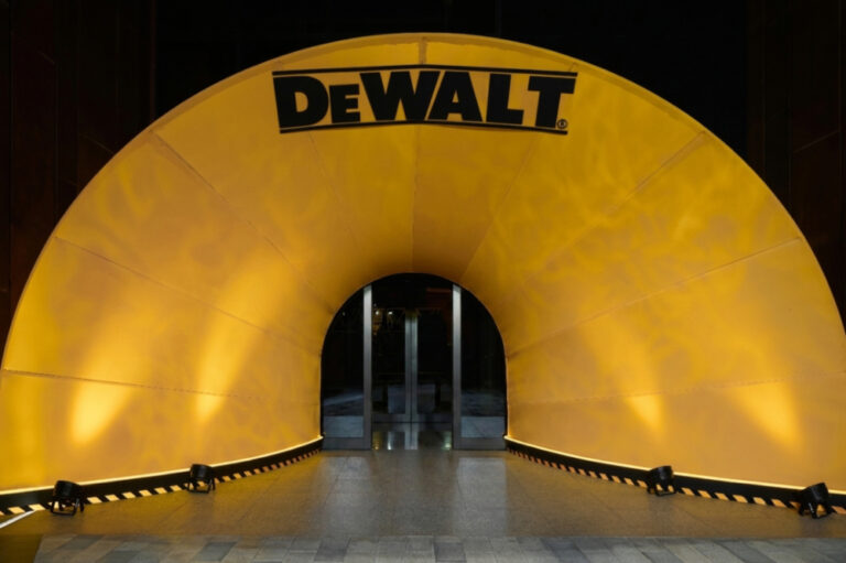 DeWalt branded archway with bright yellow lighting at building entrance, symbolizing construction and power tools.