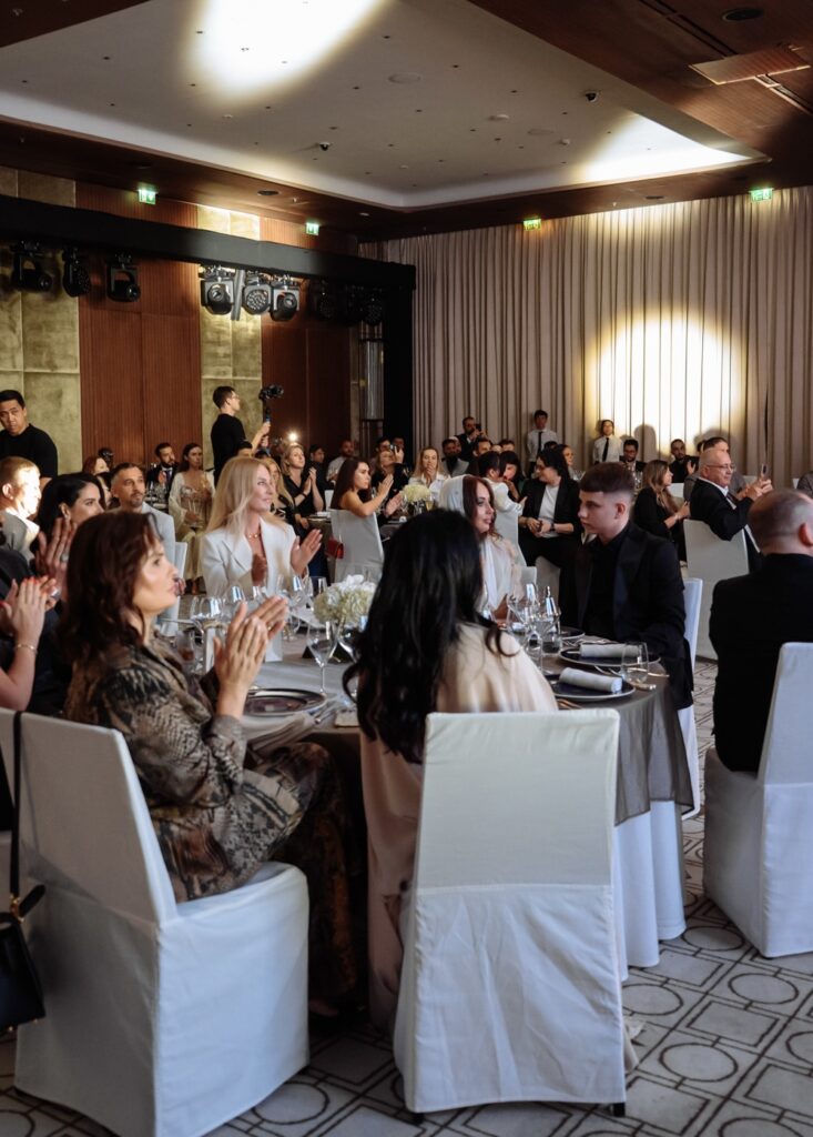 Elegant banquet with guests applauding at a formal event in a beautifully lit ballroom.