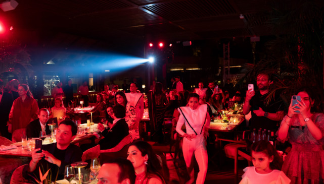 People enjoying a lively nighttime event with vibrant lighting and socializing in a warmly lit venue.